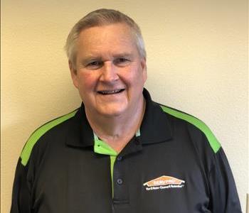 Photo of a man in black SERVPRO polo in front of a blank wall 